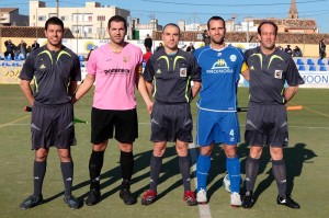 El trío arbitral con los capitanes del partido