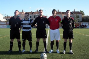 El trio arbitral con los capitanes del partido