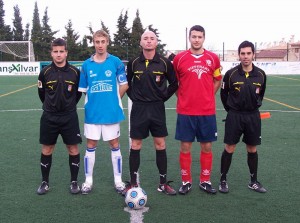 El trío arbitral con los capitanes del partido