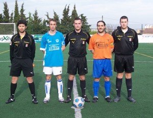 El trío arbitral con los capitanes del partido