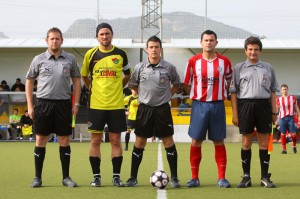 El trío arbitral con los capitanes del partido