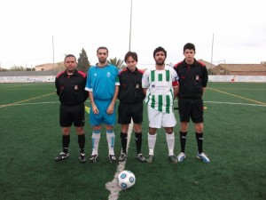 El trio arbitral con los dos capitanes del partido