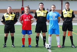 El trío arbitral con los capitanes del partido