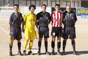 El trío arbitral con los capitanes del partido